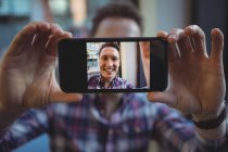 Jeune homme prenant selfie sur téléphone portable à la cafétéria — Photo de stock