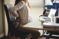 Вагітна бізнес-леді тримає болючу спину, сидячи на стільці в офісі — стокове фото