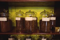 Close-up de frascos de grãos de café dispostos na prateleira na loja — Fotografia de Stock