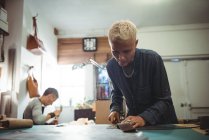 Aufmerksame Handwerkerin schneidet Leder in Werkstatt — Stockfoto