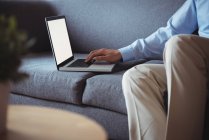 Seção média do homem usando laptop na sala de estar em casa — Fotografia de Stock