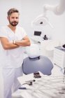 Dentist standing with arms crossed in clinic — Stock Photo