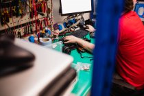 Чоловік працює на настільному комп'ютері в центрі ремонту електроніки — стокове фото