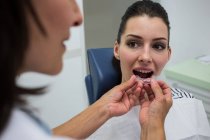 Стоматолог, помогающий пациенту носить ортодонтические силиконовые невидимые брекеты — стоковое фото