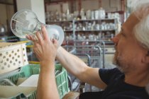 Стеклодув осматривает стеклоизделия на стекольном заводе — стоковое фото