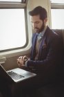 Бізнесмен перевіряє час під час використання ноутбука в поїзді — стокове фото