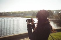 Vista trasera de la mujer tomando fotos en la cámara digital - foto de stock