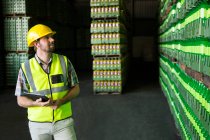 Young man examining bottles in warehouse — Stock Photo