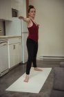 Mulher realizando alongamento ioga exercício na cozinha em casa — Fotografia de Stock