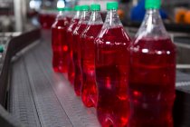 Filled red juice bottles on production line in factory — Stock Photo