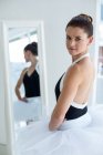 Взрослая балерина, стоящая перед зеркалом в балетной студии — стоковое фото