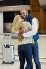 Веселая пара обнимает друг друга в зоне ожидания в терминале аэропорта — стоковое фото