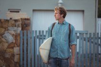 Человек с рюкзаком с доской для серфинга — стоковое фото