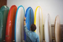 Visão traseira do homem olhando para pranchas de surf coloridas na loja — Fotografia de Stock
