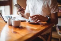 Mittelteil der Frau, die ihr Handy während einer Tasse Kaffee im Café benutzt — Stockfoto