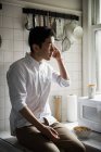 Чоловік говорить на мобільному телефоні на кухні вдома — стокове фото