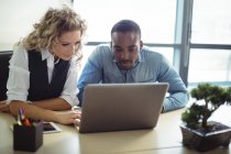 Dirigenti aziendali che discutono su laptop in ufficio — Foto stock