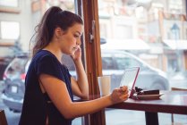 Женщина с десертом и с помощью цифрового планшета в ресторане — стоковое фото