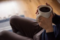 Mi-section de l'homme ayant une tasse de café noir à la maison — Photo de stock