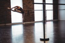 Bailarina alongamento no barre no estúdio de ballet — Fotografia de Stock