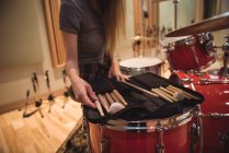 Seção média de mulher olhando para bastões de tambor em estúdio de gravação — Fotografia de Stock