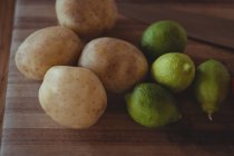 Gros plan des pommes de terre fraîches et des citrons sur tablette en bois — Photo de stock