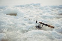 Рыболовный стержень вокруг ледяной ямы в снегу — стоковое фото