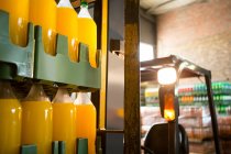 Бутылки желтого сока на вилочном погрузчике на складе — стоковое фото
