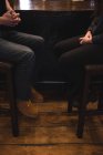 Low section of couple sitting on stools at bar counter — Stock Photo