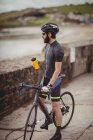 Athlete refreshing from bottle while riding bicycle on road — Stock Photo