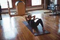 Frau übt Pilates auf Gymnastikmatte im Fitnessstudio — Stockfoto