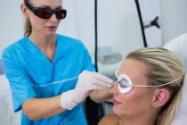 Dermatólogo ajustando gafas protectoras en salón de belleza - foto de stock
