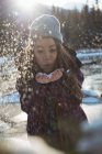 Femme soufflant la neige par la rivière en hiver — Photo de stock