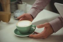 Close-up de mãos pegando xícara de café no café — Fotografia de Stock