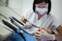 Dentista examinando paciente con herramientas de odontología en clínica - foto de stock