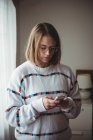 Женщина с помощью мобильного телефона в номере дома — стоковое фото