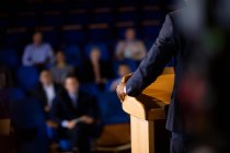 Mid section of male business executive giving a speech at conference center — Stock Photo