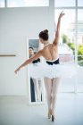 Балерина практикует балет перед зеркалом в студии — стоковое фото