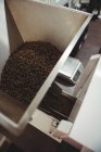 Grãos de café derramados dentro da máquina de torrefação de café no café — Fotografia de Stock