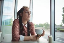 Femme réfléchie prenant une tasse de café dans un café — Photo de stock