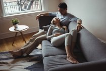 Casal romântico no sofá interagindo uns com os outros em casa — Fotografia de Stock