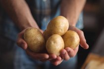 Крупним планом рука тримає свіжу сиру картоплю — стокове фото