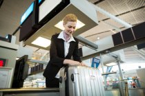 Auxiliar de check-in de la aerolínea pegado al equipaje del viajero en el aeropuerto - foto de stock