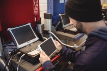 Mecánico celebración tableta digital en el garaje de reparación - foto de stock