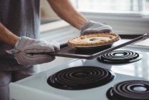 Meados de seção de homem segurando uma bandeja de torta recém-assada na cozinha em casa — Fotografia de Stock