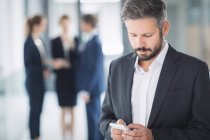 Бизнесмен использует мобильный телефон в офисном здании — стоковое фото