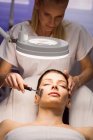 Female dermatologist performing laser hair removal on patient face in clinic — Stock Photo