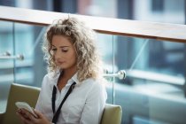 Blonde Geschäftsfrau benutzt Handy auf Büroflur — Stockfoto