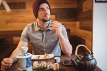 Вдумчивый человек ест суши в ресторане — стоковое фото