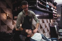 Barbier mettre serviette sur le client dans le salon de coiffure — Photo de stock
